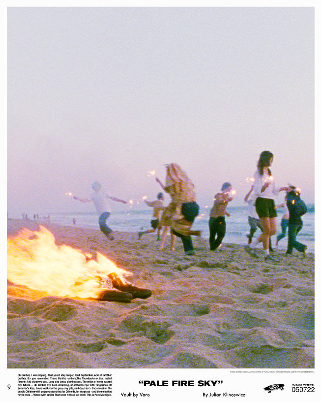 9 People holding lit sparklers on beach with a small fire on sand