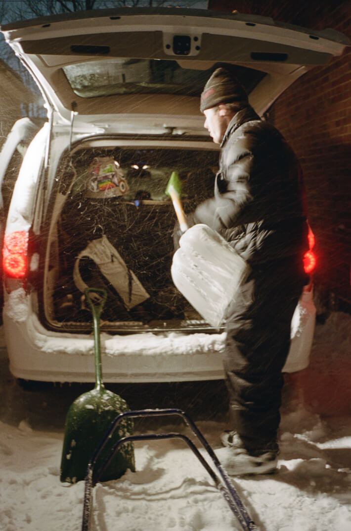 Cole Navin wearing his signature Hi Standard Pro boots and getting a snow shovel out of the trunk of a car.
