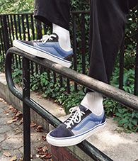 Knee-down view of a person wearing blue Vans Old Skool 36+ shoes outdoors.