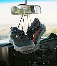 A pair of Black Vans MTE pride collection shoes hanging from a car's rearview mirror.