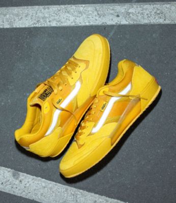 A pair of yellow AVE 2.0 skate shoes on concrete.