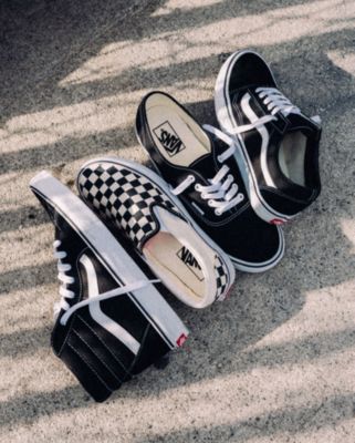 Vans black sk8 hi shoe, authentic shoe, old skool shoe and checkerboard slip on shoe laying outside on the cement.