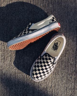 Vans black and white checkerboard slip on shoes on the cement