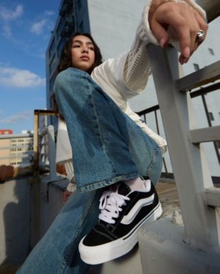 A girl city outside on a city rooftop wearing Vans black and white knu skool youth shoes.