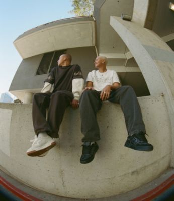 Two people sitting on a wall looking over their shoulders wearing black and white upland shoes.