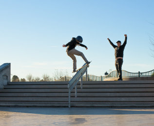 A skateboarder doing a trick with a man cheering them on.