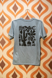A grey tshirt from The Lizzie collection hanging on a brown and orange patterned wall.